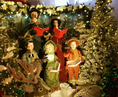Five animatronic carolers sing in between Christmas trees.