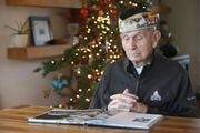 Pearl Harbor survivor Dick Higgins, 102, looks at the book "Pearl Harbor: The Day of Infamy — An Illustrated History" during a moment of reflection Tuesday at home in Bend.