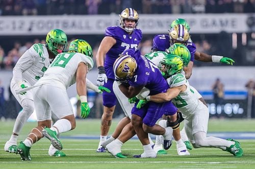 An Oregon defender (right) wraps up Washington running back Dillon Johnson (7) as the No. 5 Ducks take on the No. 3 Huskies in the Pac-12 championship game on Friday, Dec. 1, 2023, at Allegiant Stadium in Las Vegas.