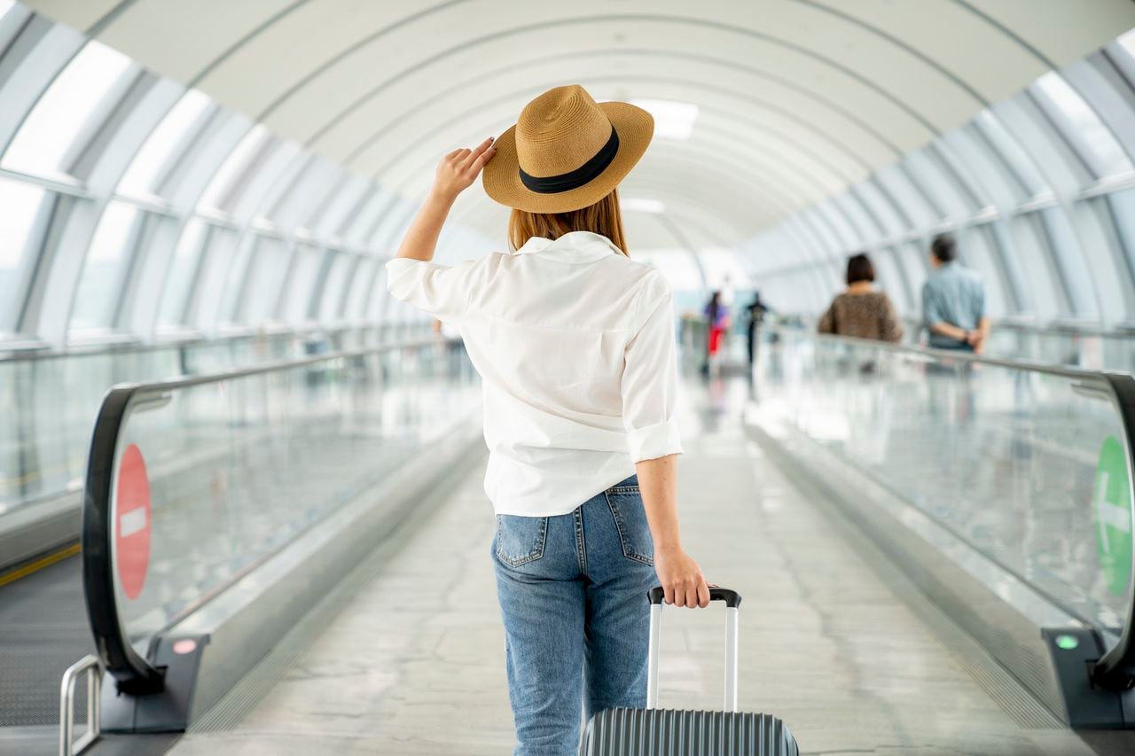 Young casual female traveler with suitcase at airport