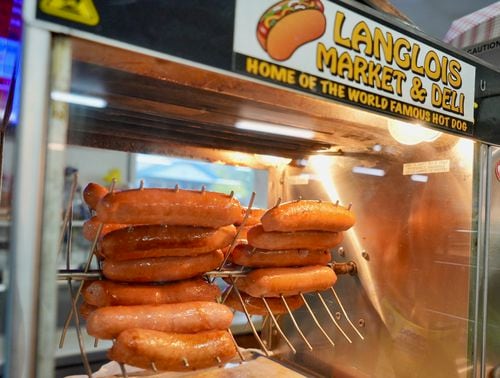 hot dogs on a warming rotisserie on a store counter, with a sticker at top that reads Langlois Market & Deli, home of the world famous hot dog
