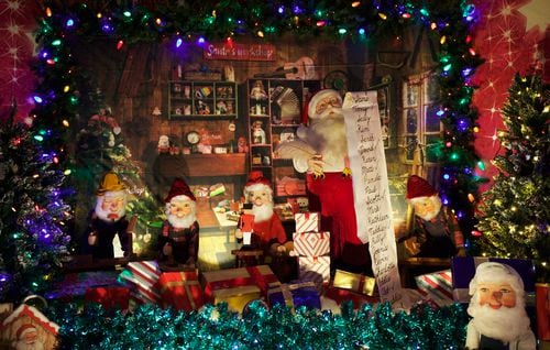 An animatronic Santa reads his list surrounded by elves.